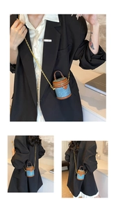 Macro shot of micro denim bucket bag with brown leather trim and golden chain strap