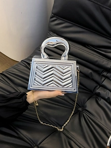 Detail of silver metallic handbag with wave texture and unique curved top handle