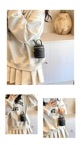 Detail of black mini cylinder crossbody bag featuring pebbled leather and gold chain