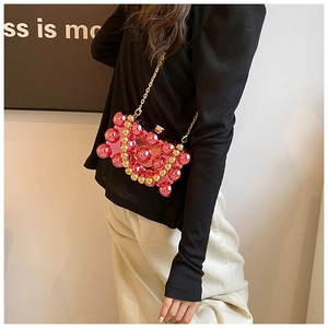 Detail of pink acrylic crossbody bag with gold metallic beads and fine chain strap