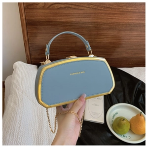 Dettaglio della borsa ottagonale in pelle azzurra con cornice dorata e testo moda