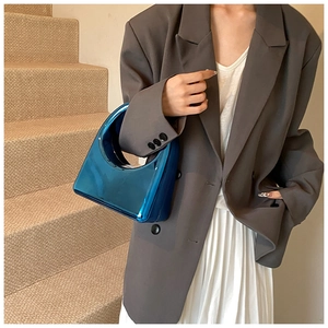 Sac à main en acrylique bleu métallisé avec finition miroir porté par un mannequin