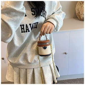 Mini bucket bag detail showing off-white fabric and brown leather with chain strap