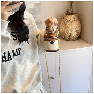 Mini bucket crossbody bag in cream and brown leather shown on a model for scale
