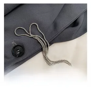 Close-up of polished silver snake chain hardware detail on a fashion evening bag