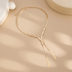 Close-up of golden snake chain Y-necklace featuring an intertwined knot and tassel detail