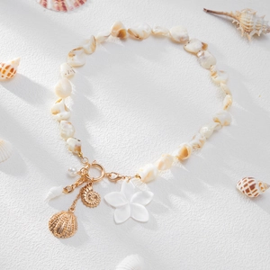 Handgefertigte Muschelkette mit goldenem Seestern- und Schneckenanhänger auf weißem Grund