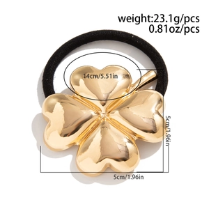 Macro view of gold four-leaf clover charm with black elastic ponytail holder loop