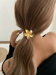 Close-up of a golden flower hair tie with five petals on a ponytail hairstyle