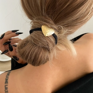 Minimalist black hair tie featuring a gold hammered heart pendant in a low ponytail