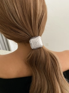 Close-up of a silver hammered metal hair tie accessory styled on a low ponytail ponytail