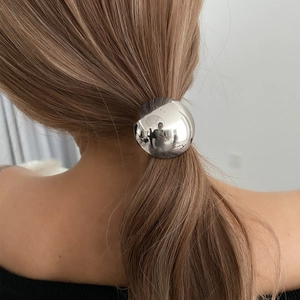Close-up of a minimalist silver mirror ball hair tie worn on a ponytail hair style