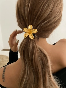 Close-up of golden flower hair tie worn on a ponytail with high-elastic black band