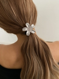 Detailed view of a silver floral hair clip styled on a woman's ponytail accessory