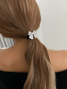 Detail of silver textured bow hair tie on ponytail with black elastic band
