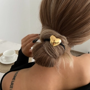 Detail of a shiny gold heart pendant hair tie worn on an elegant updo hairstyle