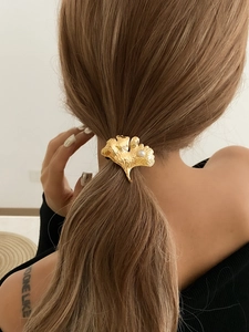 Close-up of golden ginkgo leaf hair clip with pearl detail on woman's ponytail