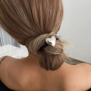 Silver heart pendant hair tie shown decorating a bun hairstyle on a model