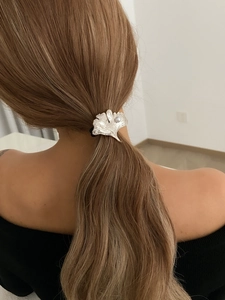 Detail view of silver ginkgo leaf ponytail holder with pearl on black elastic hair tie