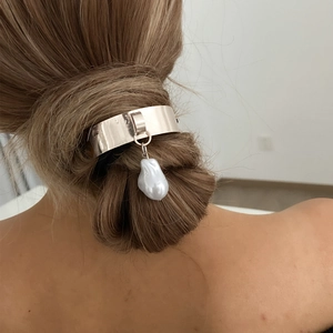 Close-up of heart-shaped silver metal hair tie with a baroque pearl on a low bun