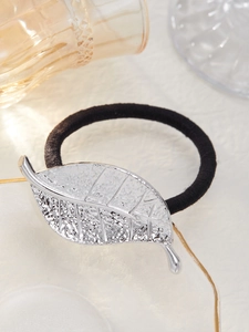 Detailed close-up of a silver leaf hair tie with metallic texture and matte finish
