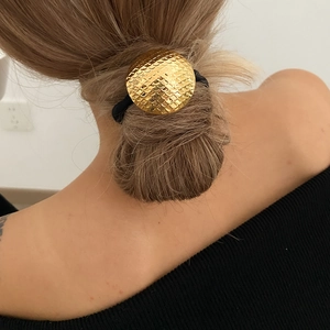 Detailed view of golden heart hair tie with fish scale texture on a ponytail