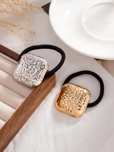 Detailed close-up of gold and silver square hammered texture metal hair ties on jewelry tray