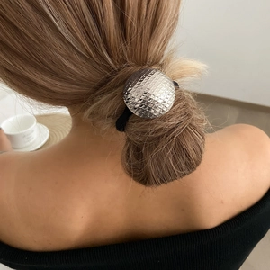 Detailed view of silver textured metal hair tie on a high ponytail for elegant styling