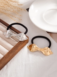 Detail view of gold and silver metallic bow hair ties with fine brushed texture