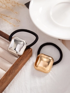 Macro shot of gold and silver square metal charms on black elastic ponytail holders
