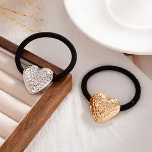 Close-up of heart-shaped hair ties in gold and silver with textured hammered finish