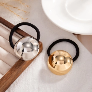 Detail of gold and silver metallic ball hair ties on a minimalist tray with dried flowers