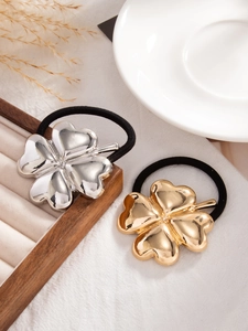 Detailed close-up of clover ponytail holders in gold and silver finish on tray