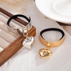 Close-up of gold and silver heart charms on black elastic hair ties for ponytails