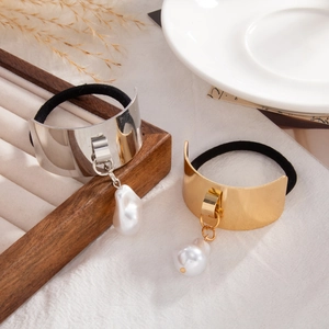 Detailed shot of golden and silver heart hair ties with baroque pearl charms on wood