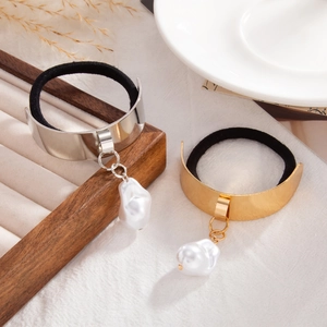 Detail of gold and silver metallic hair ties with hanging baroque pearls on white fabric