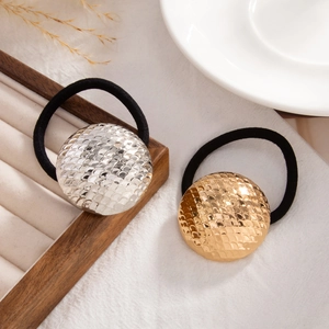 Detailed close-up of gold and silver dome hair ties with fish-scale texture and black elastic