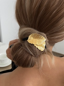 Détail d'un élastique cheveux feuille dorée montrant le fini brossé sur un chignon