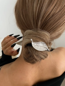 Détail d'une pince à cheveux feuille argentée avec texture nervurée sur coiffure