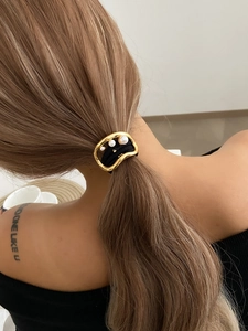 Detail of irregular gold metal hair ring with gradient pearls on a brown ponytail