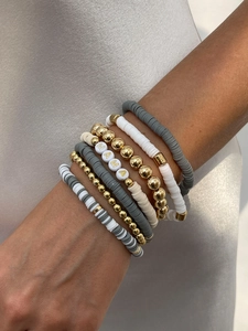 Close-up of stacked colorful Heishi bead bracelets with MAMA gold letter beads