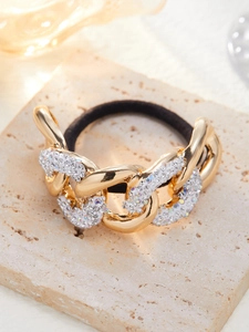 Macro-opname van gouden haarelastiek met strass steentjes op beige stenen ondergrond