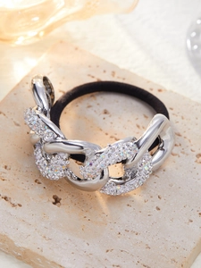 Detail van zwarte haarelastiek met zilveren ketting en sprankelende kleurrijke strasstenen