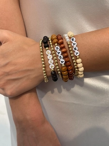 Detail of bohemian multilayer beaded bracelets with MAMA letter beads and wooden charms