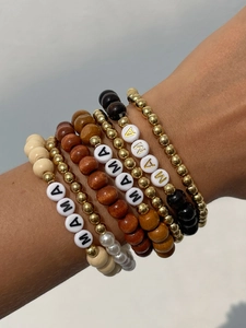 Close-up of stacked bohemian bracelets with wood beads and MAMA letter charms