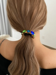 Detail of luxury hair tie with emerald and sapphire crystal stones on a low ponytail