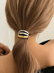 Detail of mixed metal ponytail holder with silver and gold wavy mirror finish on hair