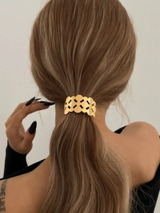 Detail of a hollow geometric gold metal hair cuff clip on a low ponytail hairstyle