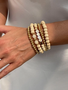 Detail of stacked bohemian bracelets with wood beads and MAMA letter charms on wrist