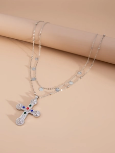 Close-up of double-layered silver necklace with a large gemstone-inlaid cross pendant